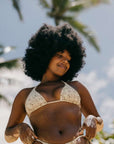 Model wearing a Hawaiian themed bikini standing with plam trees behind her.